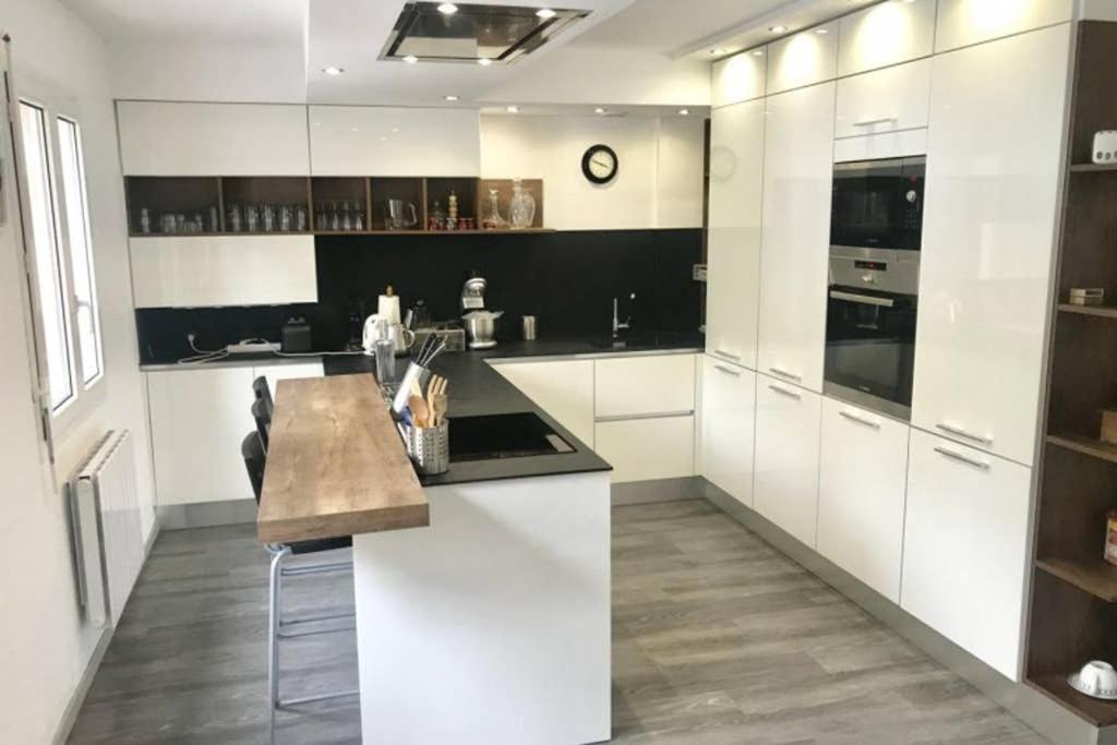 a kitchen with white cabinets and a wooden counter top at Chalet Étoile des neiges in Barèges