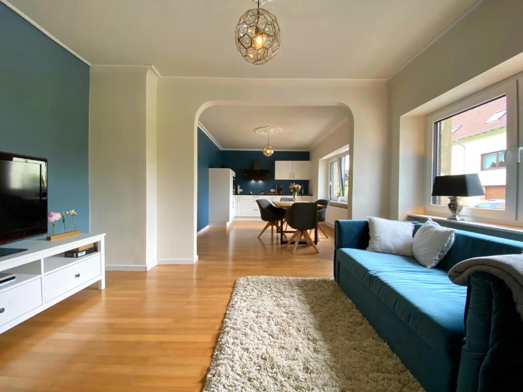 uma sala de estar com um sofá azul e uma televisão em Ferienwohnung SeeGlück em Nohfelden