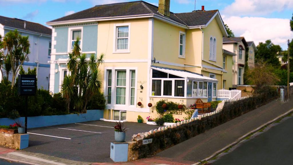 una casa amarilla con un estacionamiento delante de ella en Marmalade Bed & Breakfast, en Torquay