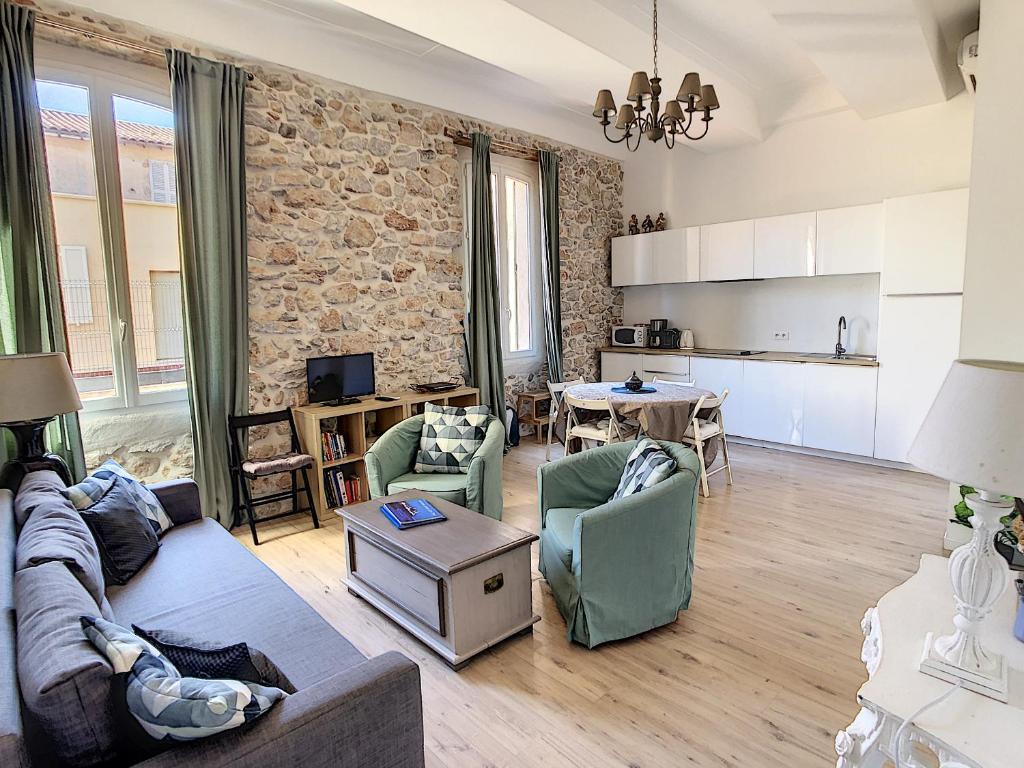 a living room with a couch and chairs and a kitchen at Hanna-Logis in Antibes