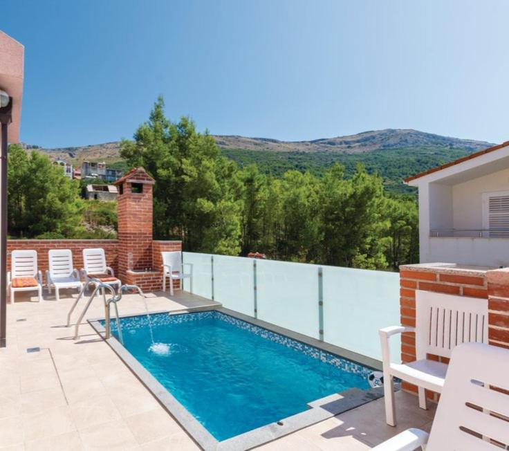 una piscina en un patio con sillas blancas en Apartman Relax, en Podstrana