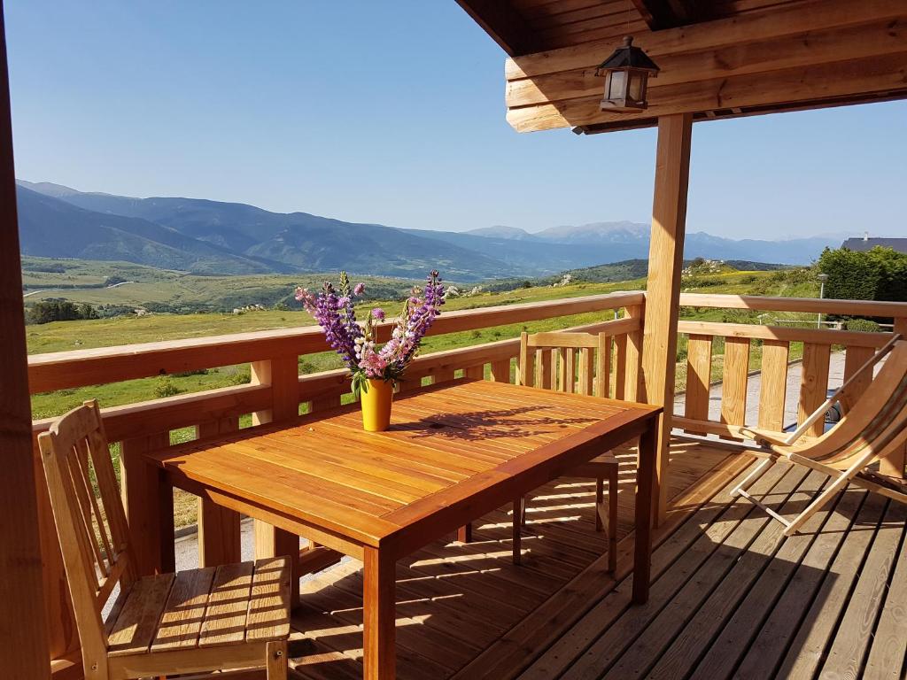 uma mesa de madeira num deque com um vaso de flores em Chalet Rouge Sorbier em Font-Romeu