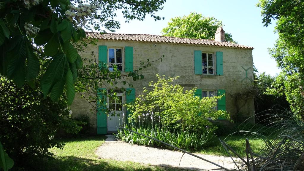 an old stone house with green shutters at Gîte La Garauderie in LʼÎle-dʼElle
