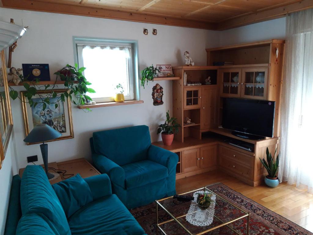 sala de estar con sofá azul y TV en Casa Trettel, en Tesero