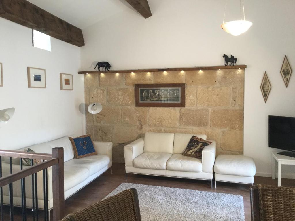 a living room with two white couches and a stone wall at Petit Paradis, 1 bedroom house in Sommières