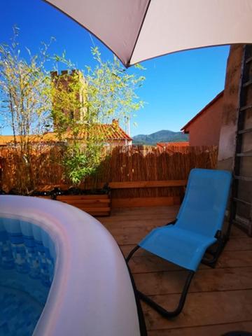 a blue chair sitting on a patio with an umbrella at Maison Small Luxury ( planxa,suite,solarium,jacuzzi,pas de vis à vis) in Argelès-sur-Mer