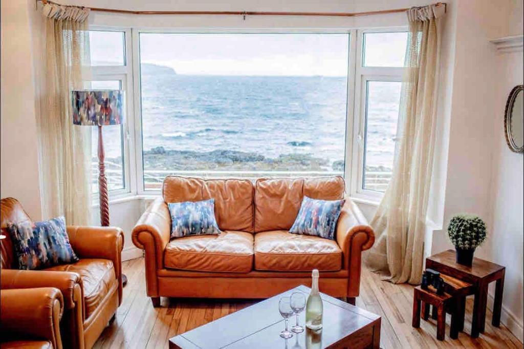 sala de estar con sofá y ventana grande en The Porthole, en Portstewart