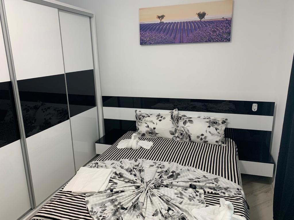 ein kleines Schlafzimmer mit einem Bett mit schwarzer und weißer Bettwäsche in der Unterkunft Apartament Mamaia Nord Coca in Mamaia Nord – Năvodari