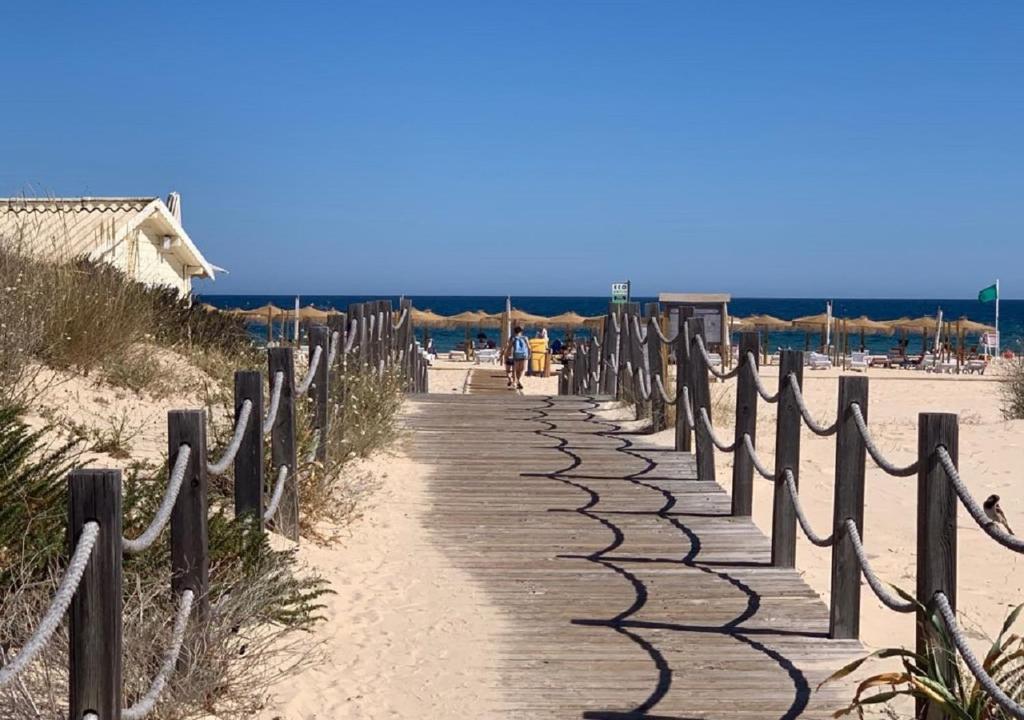 een houten pad op het strand met een hek bij T1 Luminoso junto à Praia in Altura
