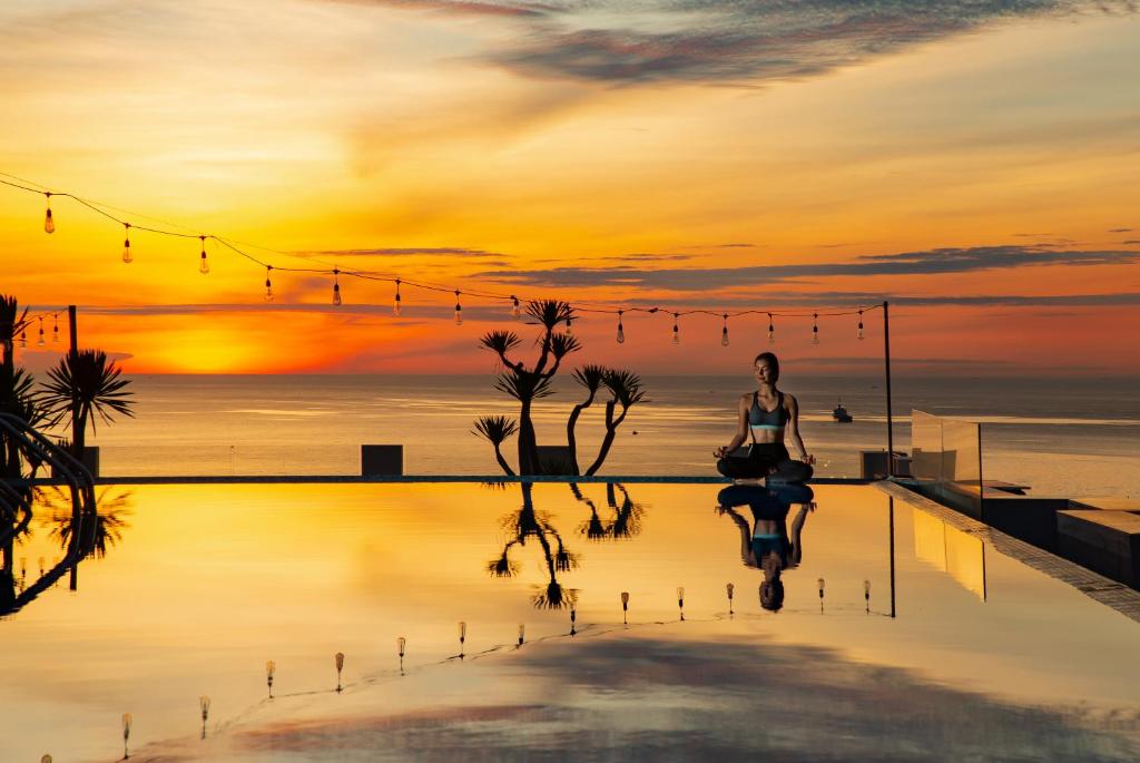 An infinity-style pool reflecting a vivid sunset over the sea.