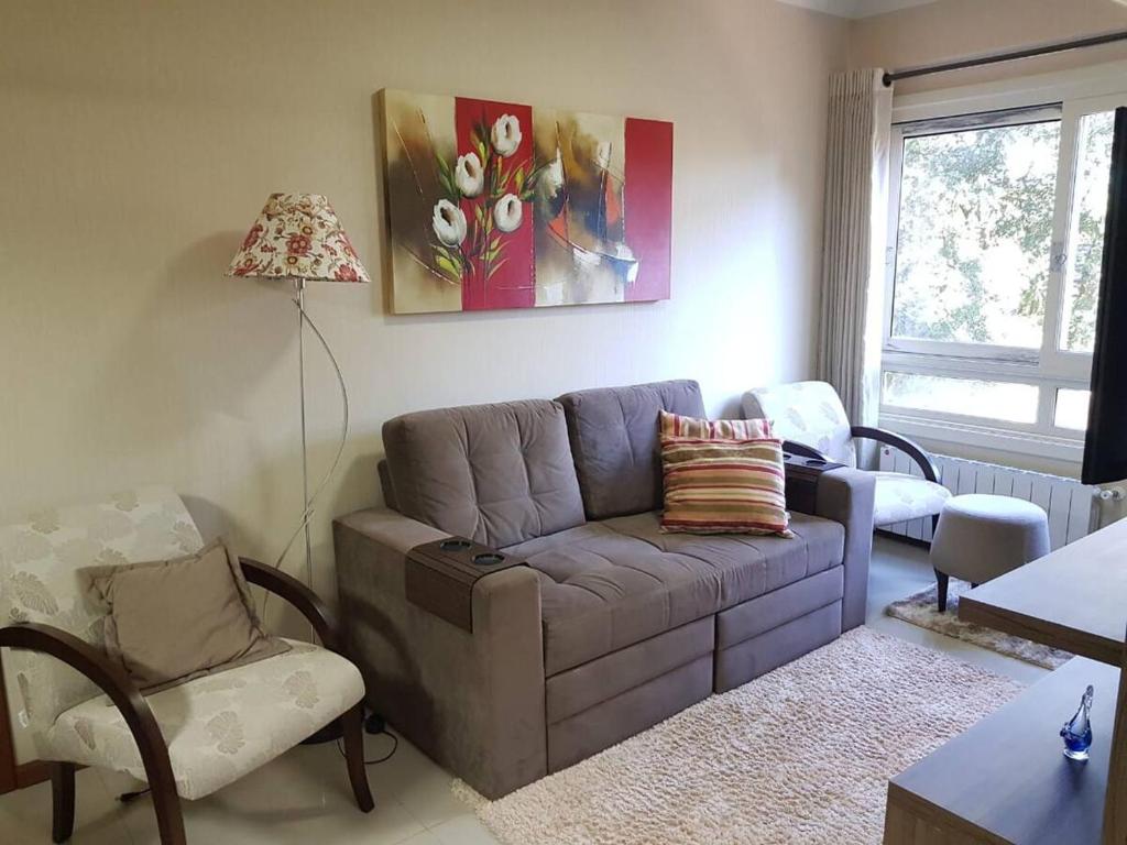 uma sala de estar com um sofá e uma cadeira em Apartamento Gramado em Gramado