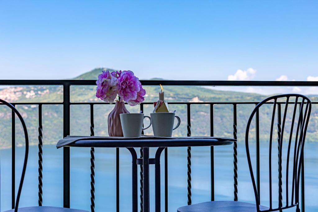 einen Tisch mit zwei Tassen und Blumen auf einem Balkon in der Unterkunft Hotel Castel Gandolfo in Castel Gandolfo