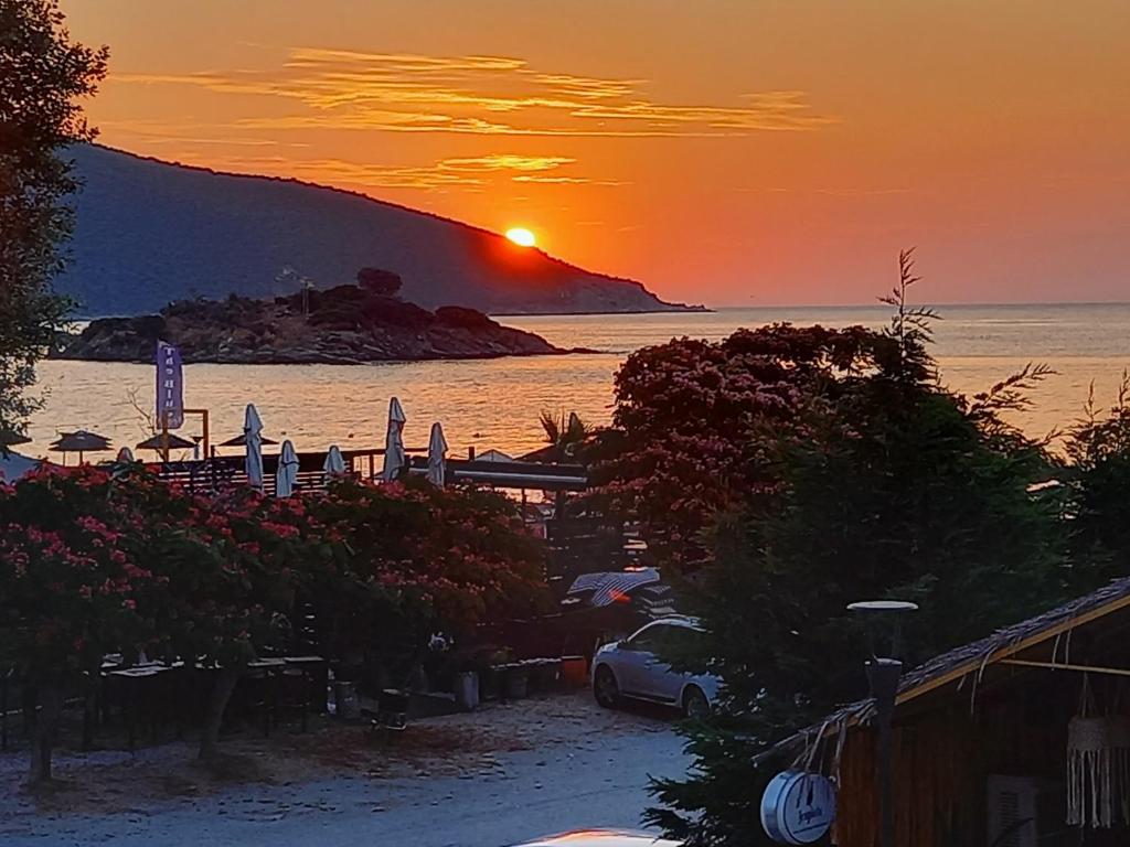 una puesta de sol en una playa con la puesta de sol sobre el agua en Leonidas Apartments, en Nea Peramos