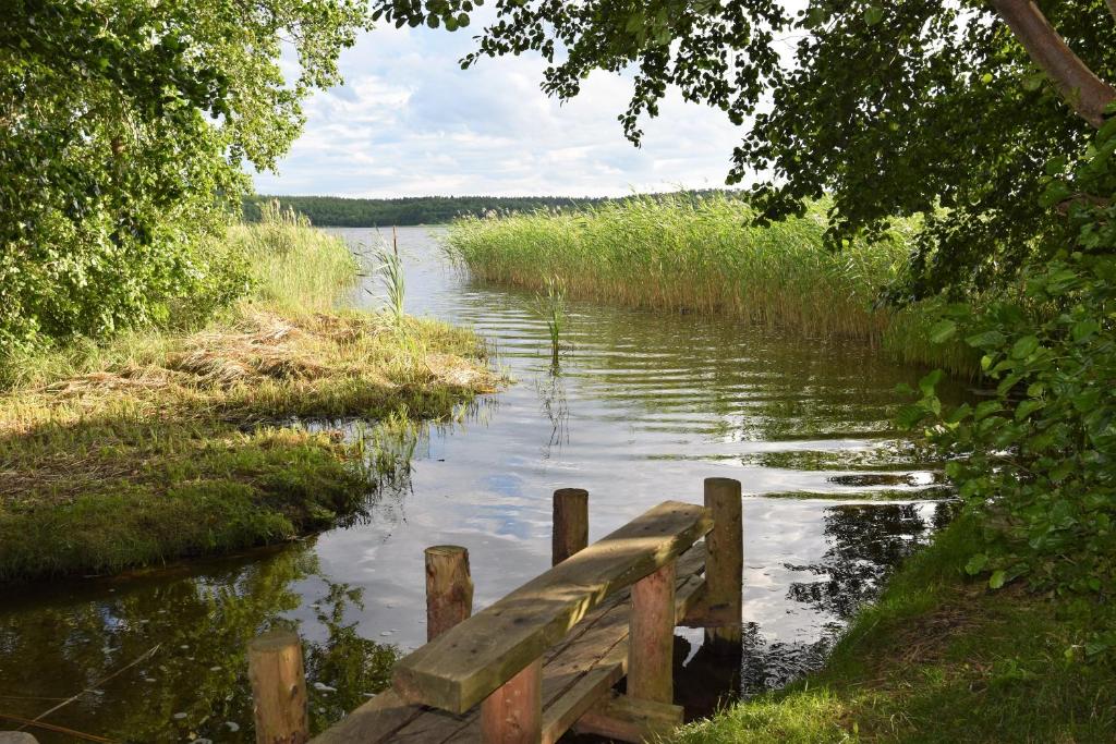 un banco de madera sentado a orillas de un río en Ferienwohnung am Bossower See, en Krakow am See