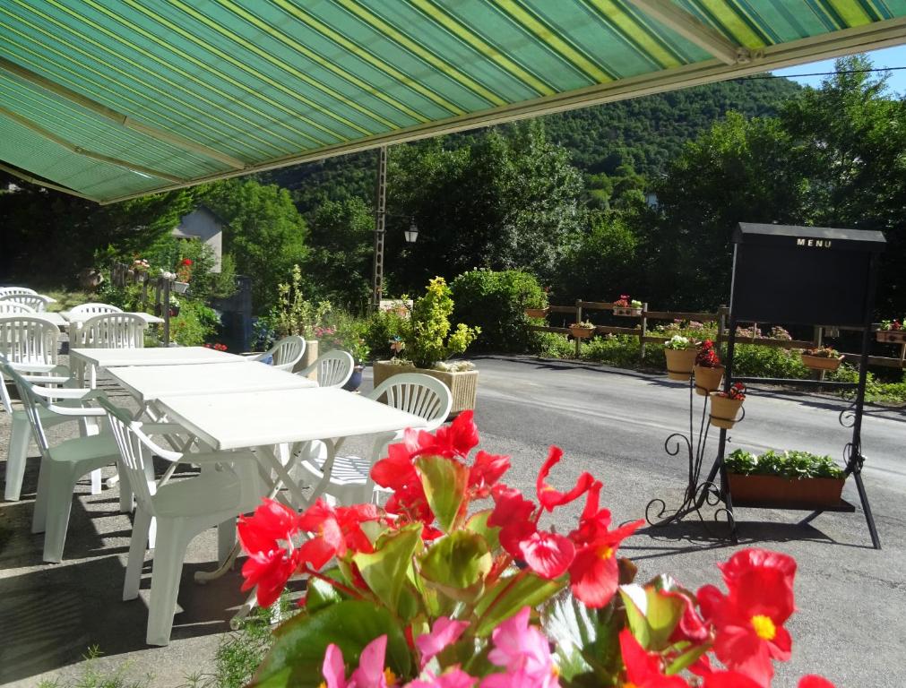 a white table and white chairs and red flowers at Les rocks in Brusque