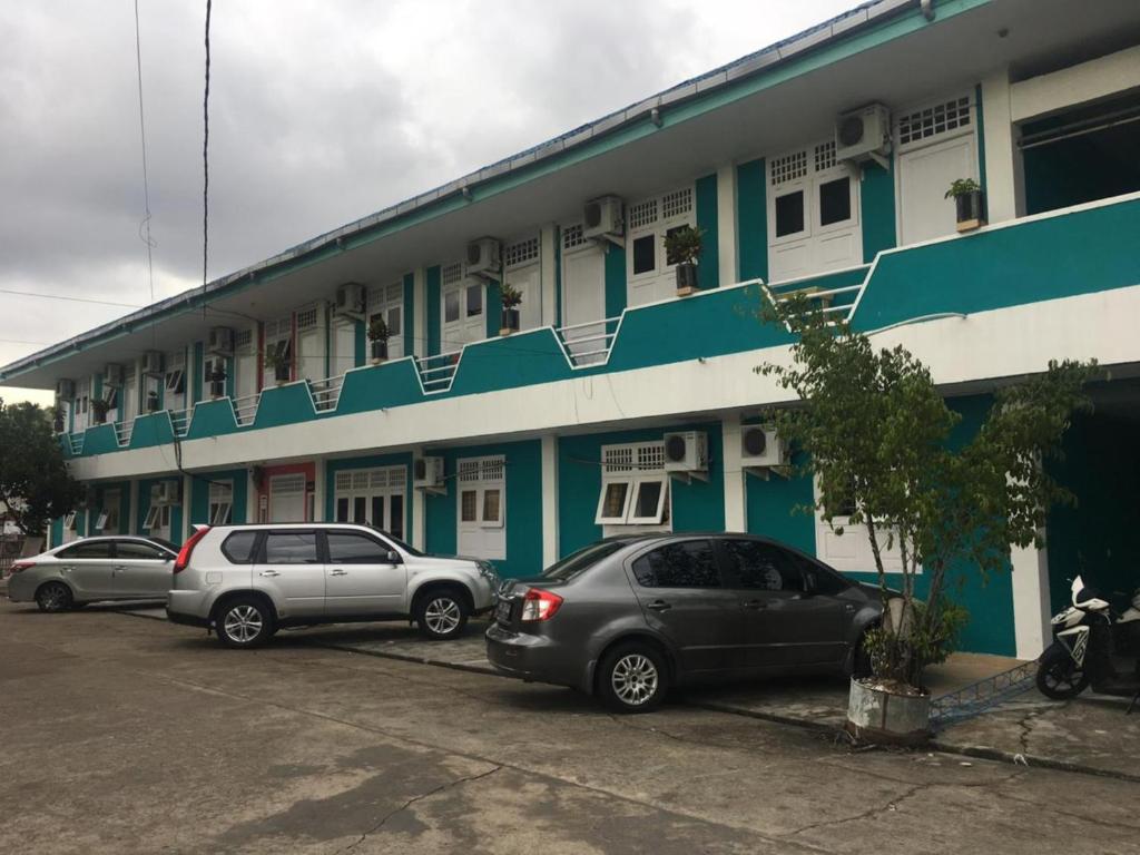 dos autos estacionados en un estacionamiento frente a un edificio en Rumah Dempo Syariah, en Sungaidurian