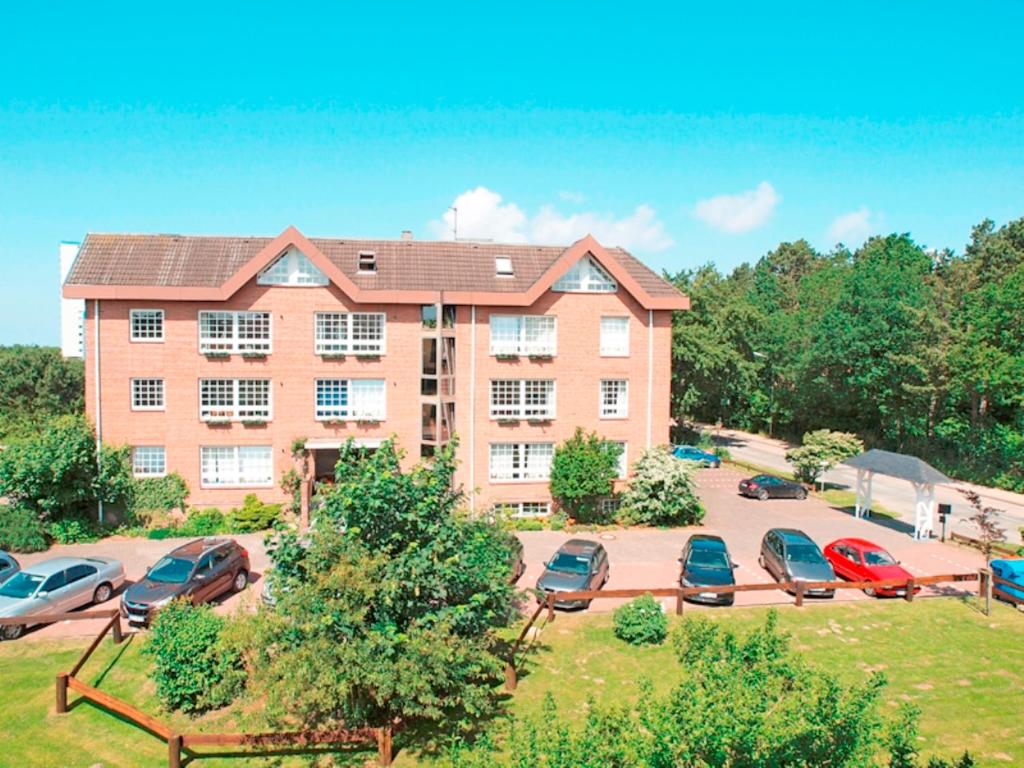 a large brick building with cars parked in a parking lot at Marbijes Appartementhaus in Cuxhaven