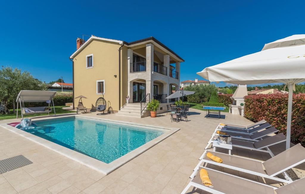 a house with a swimming pool with chairs and an umbrella at Villa Vanesa with Private Pool nearby Porec in Montižana
