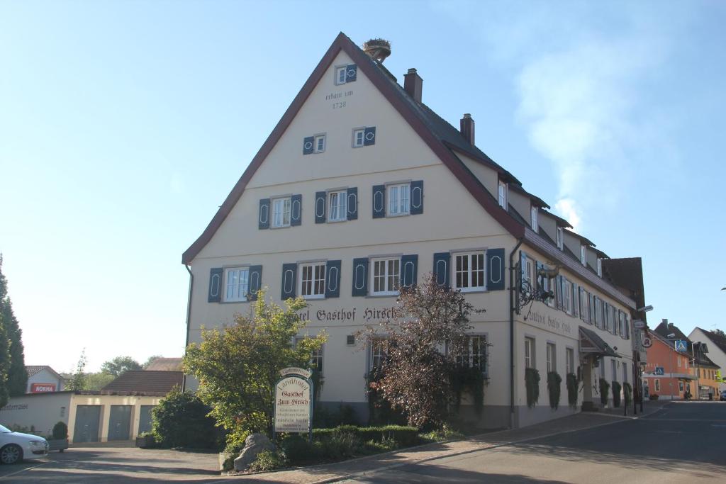 un bâtiment blanc avec un panneau devant lui dans l'établissement Gasthof Landhotel Hirsch, à Ostrach
