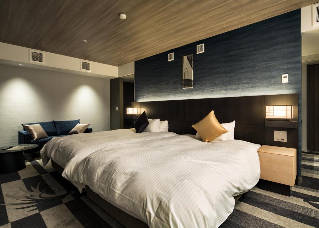 a bedroom with a large white bed and a couch at Kanazawa New Grand Hotel Prestige in Kanazawa