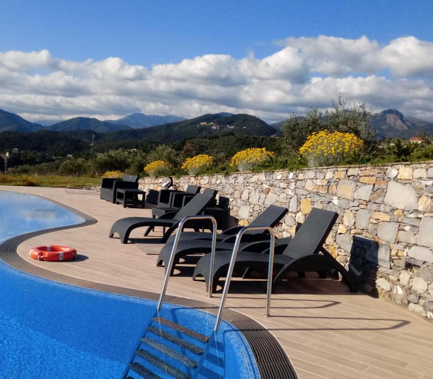 basen z krzesłami i kamienną ścianą w obiekcie Appartamento Taggiasca con piscina - Riva Trigoso w mieście Sestri Levante