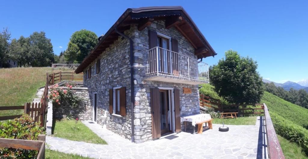 een klein stenen huis met een balkon op een heuvel bij Baita Luci in Gravedona