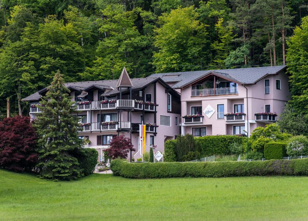 a large pink building with trees in the background at Hotel Garni ELISABETH in Pörtschach am Wörthersee