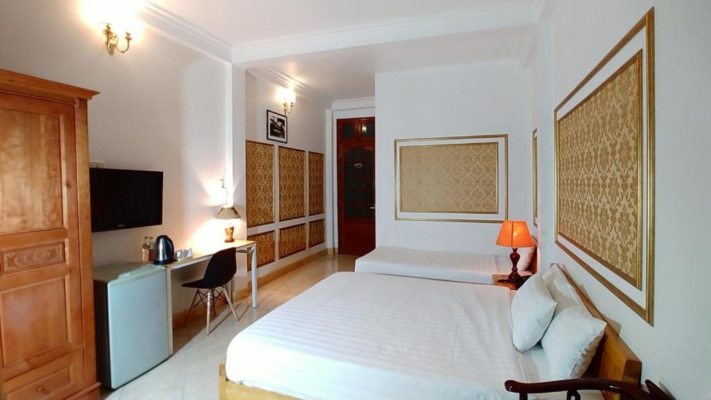 a bedroom with a bed and a desk and a television at Discovery Hotel in Hanoi