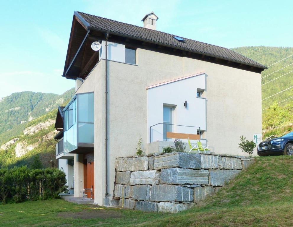 a house on a hill with a stone wall at Maison 4 soleil. Casa design luce e natura in Crodo