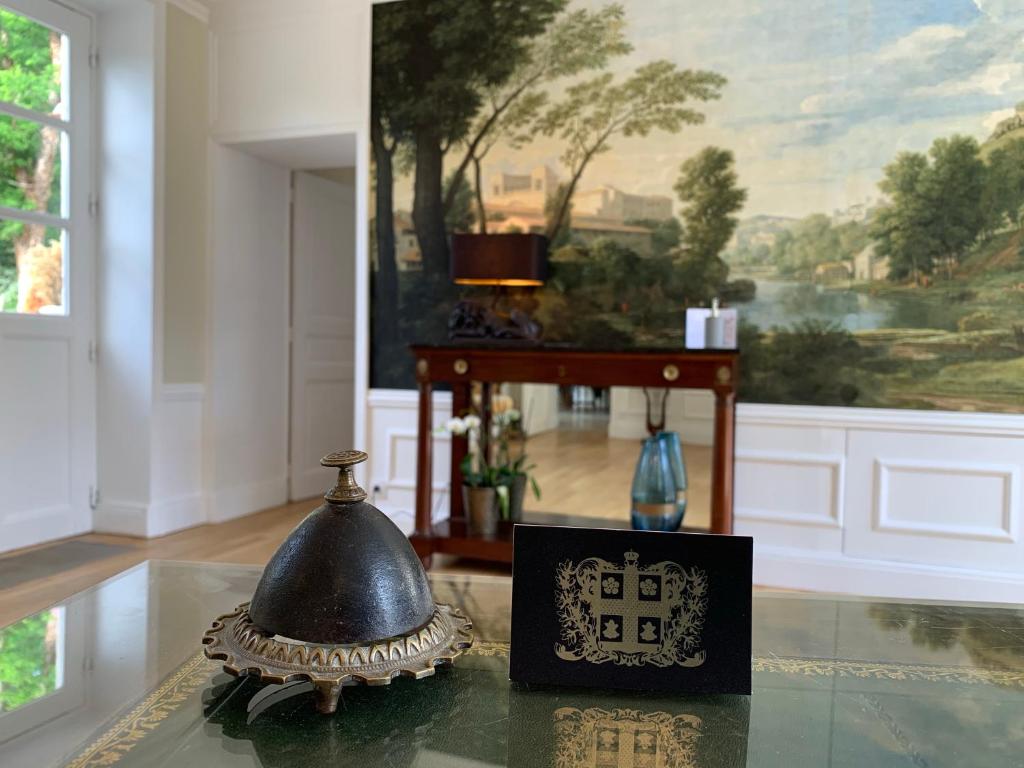 a bell on a glass table in a room with a painting at Le Tardif, Noble Guesthouse in Bayeux