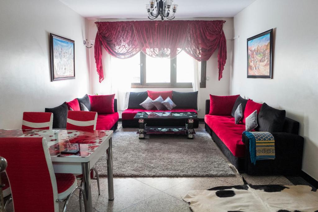 un salon avec un canapé rouge et une table dans l'établissement Modern and Cozy Apartment, à Casablanca