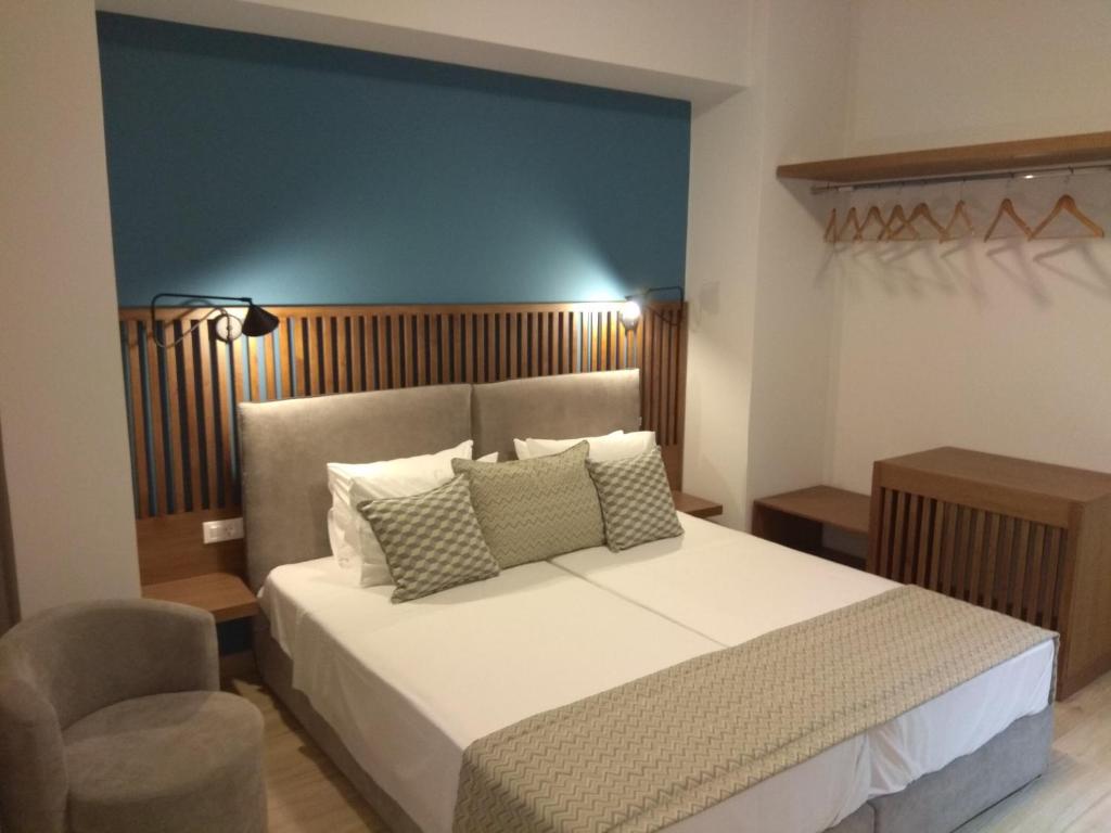 ein Schlafzimmer mit einem großen Bett und einem Stuhl in der Unterkunft Ariadni Rooms & Apartments in Ermoupoli