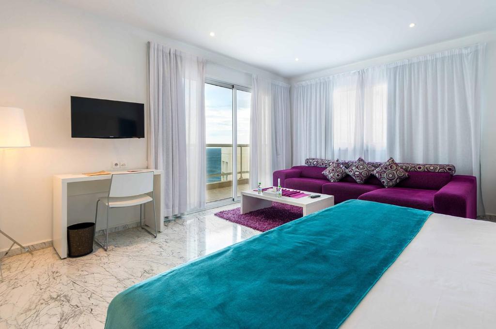 a bedroom with a large bed and a purple couch at Hotel Farah Tanger in Tangier