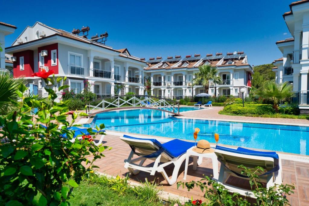 a resort with a swimming pool with two chairs and a table at Legend Apartments in Fethiye