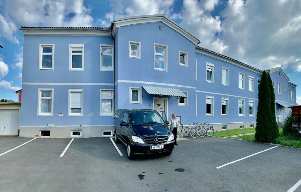 un homme debout devant un bâtiment bleu dans l'établissement Abdalla Apartments, à Knittelfeld