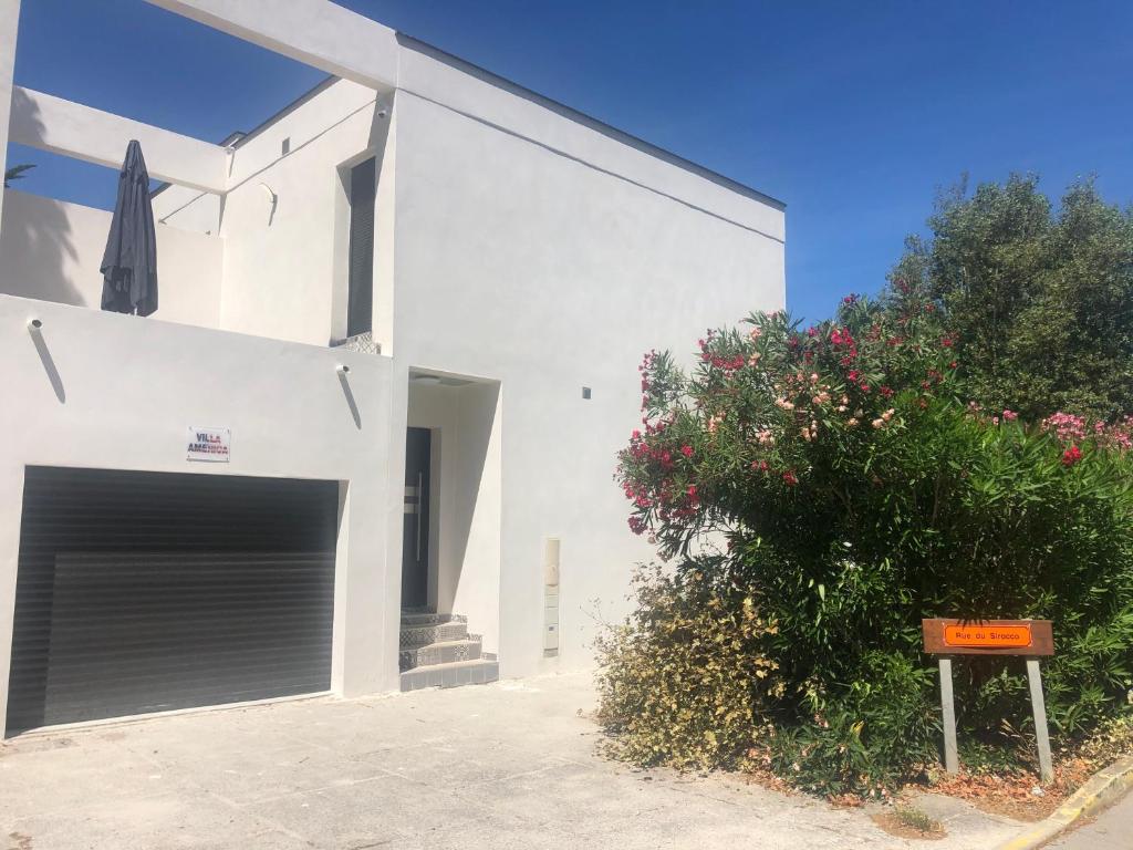 a white building with a garage door and a bush at Tahoe in La Grande Motte