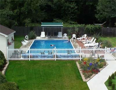 uma piscina com uma cerca branca e cadeiras em Footbridge North Hotel em Wells