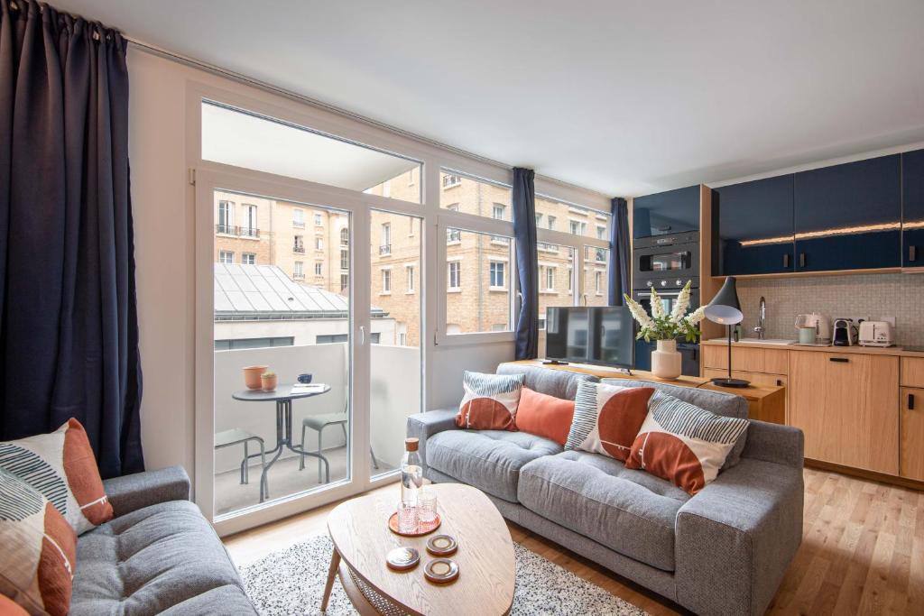 ein Wohnzimmer mit 2 Sofas und einer Küche in der Unterkunft NEW - Appt style le Corbusier avec Balcon - 8 pers in Paris