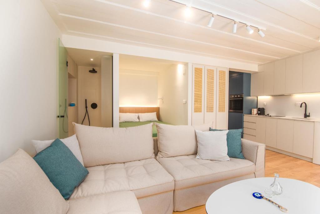 ein Wohnzimmer mit einer weißen Couch und einer Küche in der Unterkunft Liston Boutique Suites by CorfuEscapes in Korfu-Stadt
