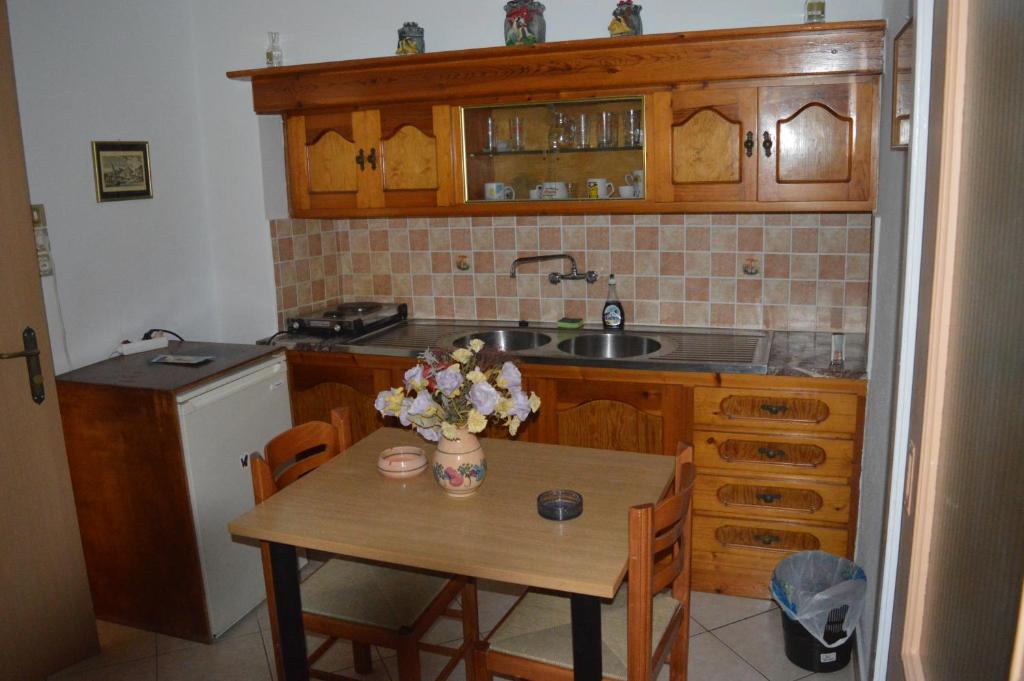 a kitchen with a wooden table and a sink and a table with flowers at HERMOUPOLI ROOMS in Ermoupoli