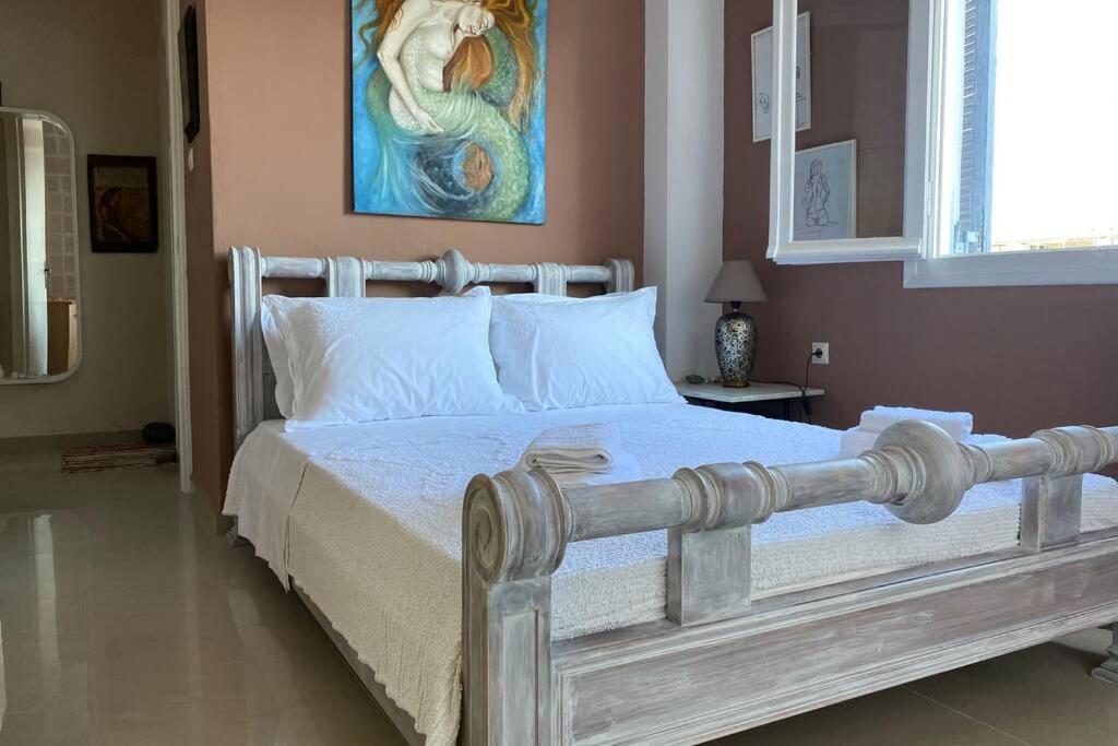 sypialnia z białym łóżkiem i obrazem na ścianie w obiekcie Marys Art and Cultural House 100meters from the beach w miejscowości Amoudara