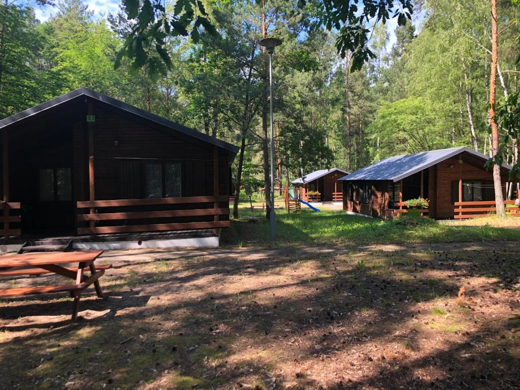 una cabaña en el bosque con un banco y un parque infantil en Leśnik Bungalow Stegna - domki letniskowe nad morzem, en Stegna