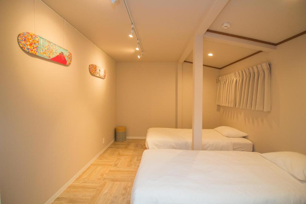 two beds in a small room with white sheets at Hokusai Stay in Osaka