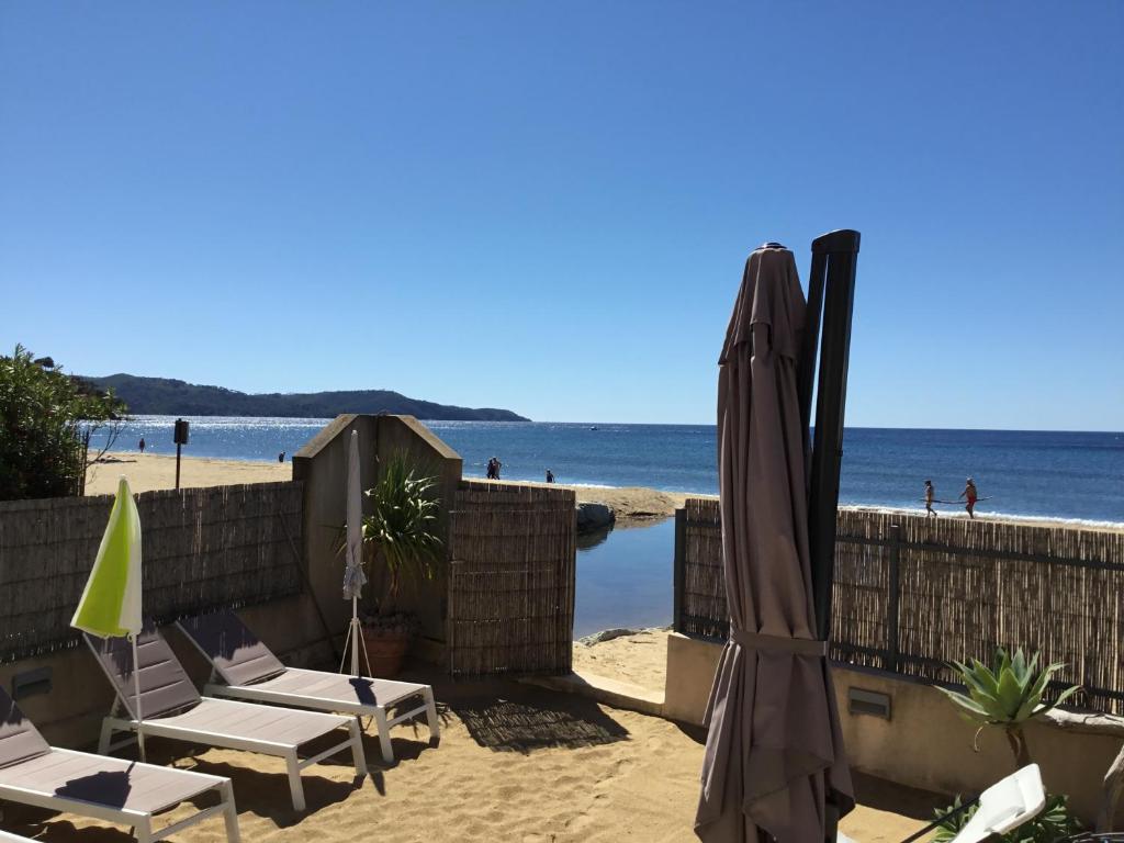 una playa con sillas y sombrilla y el océano en Résidence des Sables d'Or en La Croix-Valmer