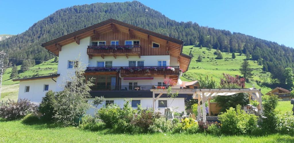 a building on a hill with a mountain at Großglocknerappartement in Kals am Großglockner