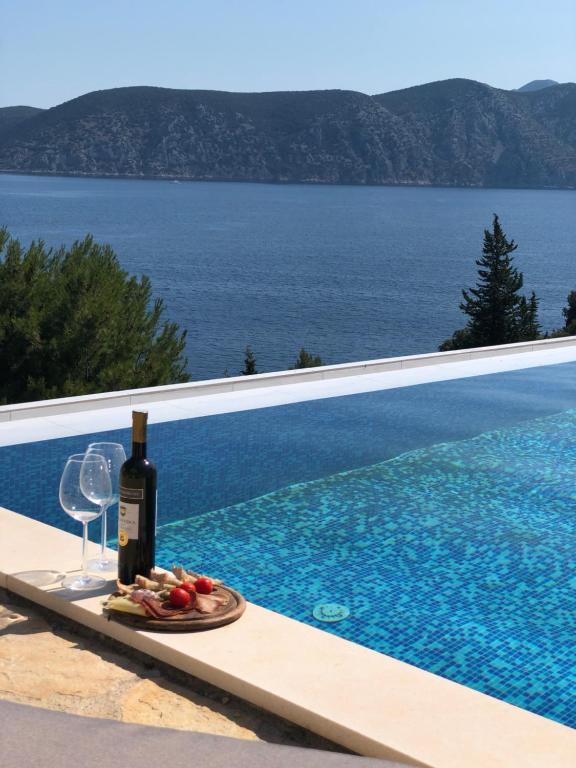 a bottle of wine and a plate of fruit next to a swimming pool at Apartments Magdalena in Račišće