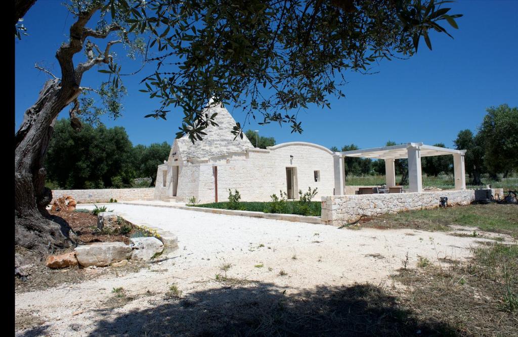 an old stone church with a tree in the foreground at Trullo Maddy in Cisternino