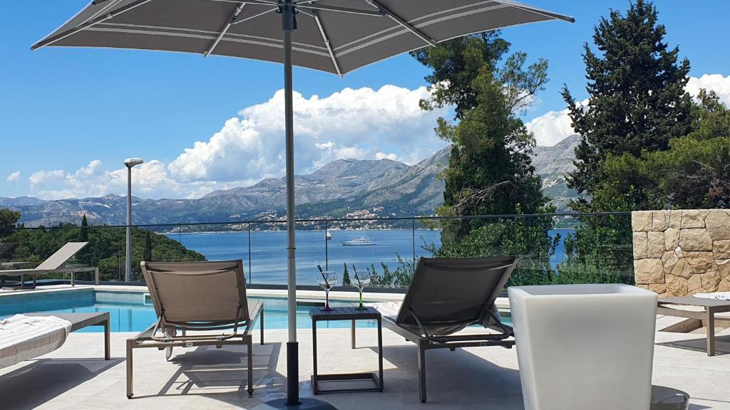a patio with chairs and an umbrella next to a pool at Hotel Seventh in Cavtat