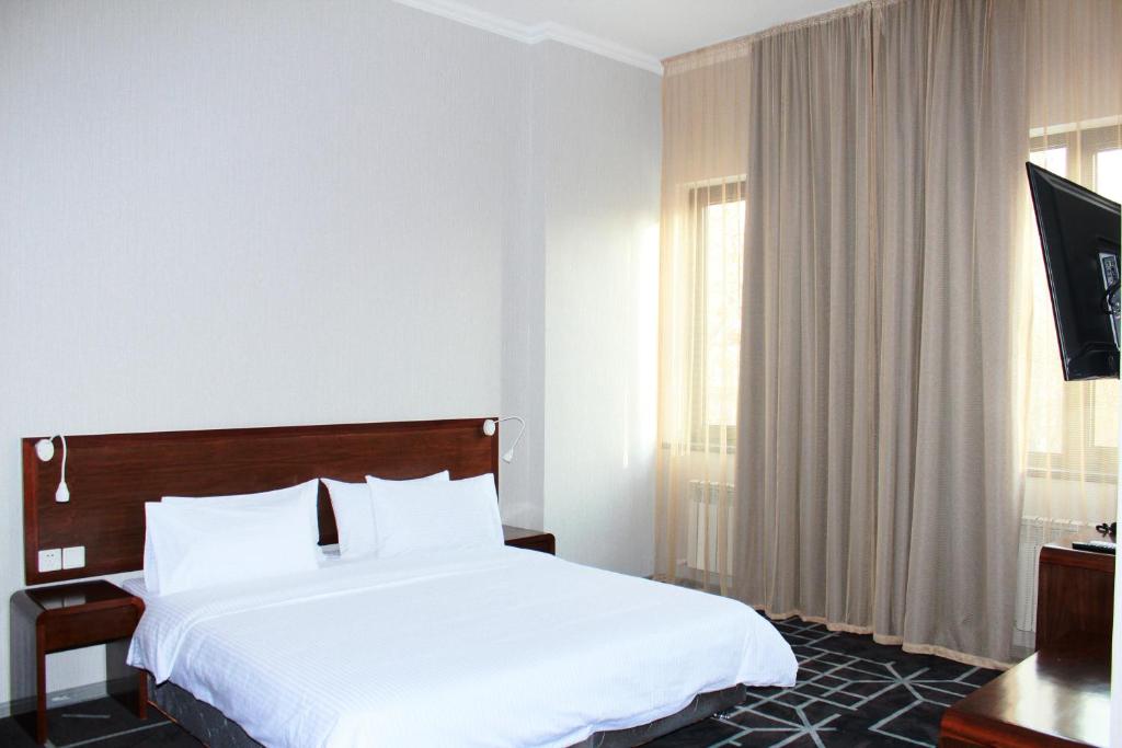 una camera d'albergo con letto e TV di City Centre Hotel a Tashkent