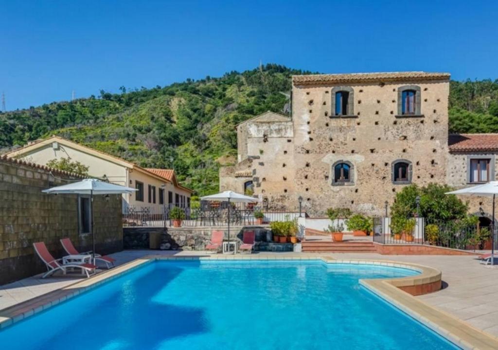 a villa with a swimming pool in front of a building at Il Borgo Country Resort in Castiglione di Sicilia